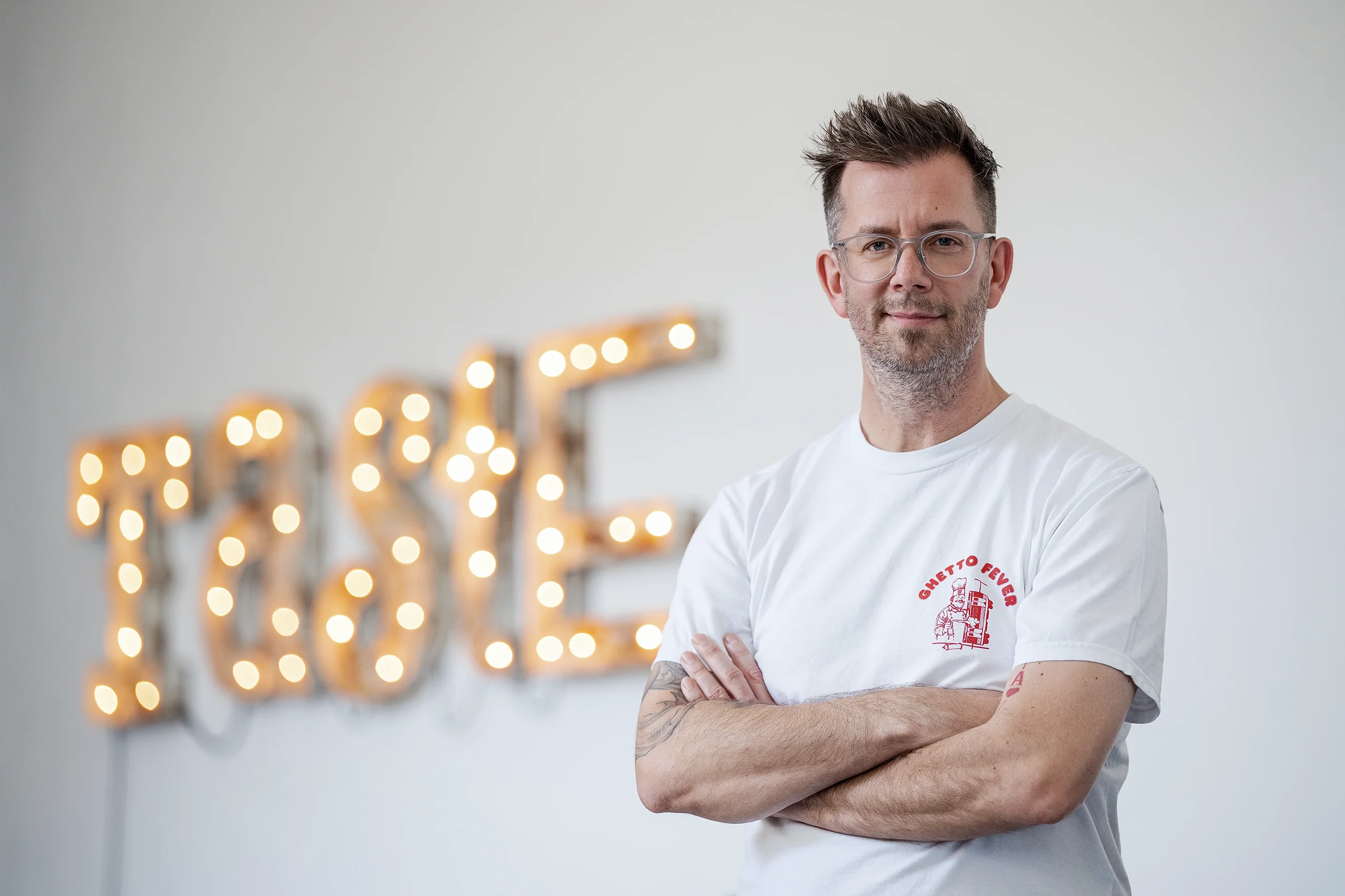 Porträt eines Creative Directors im Designstudio Haus des guten Geschmacks vor leuchtendem „Taste“-Schriftzug