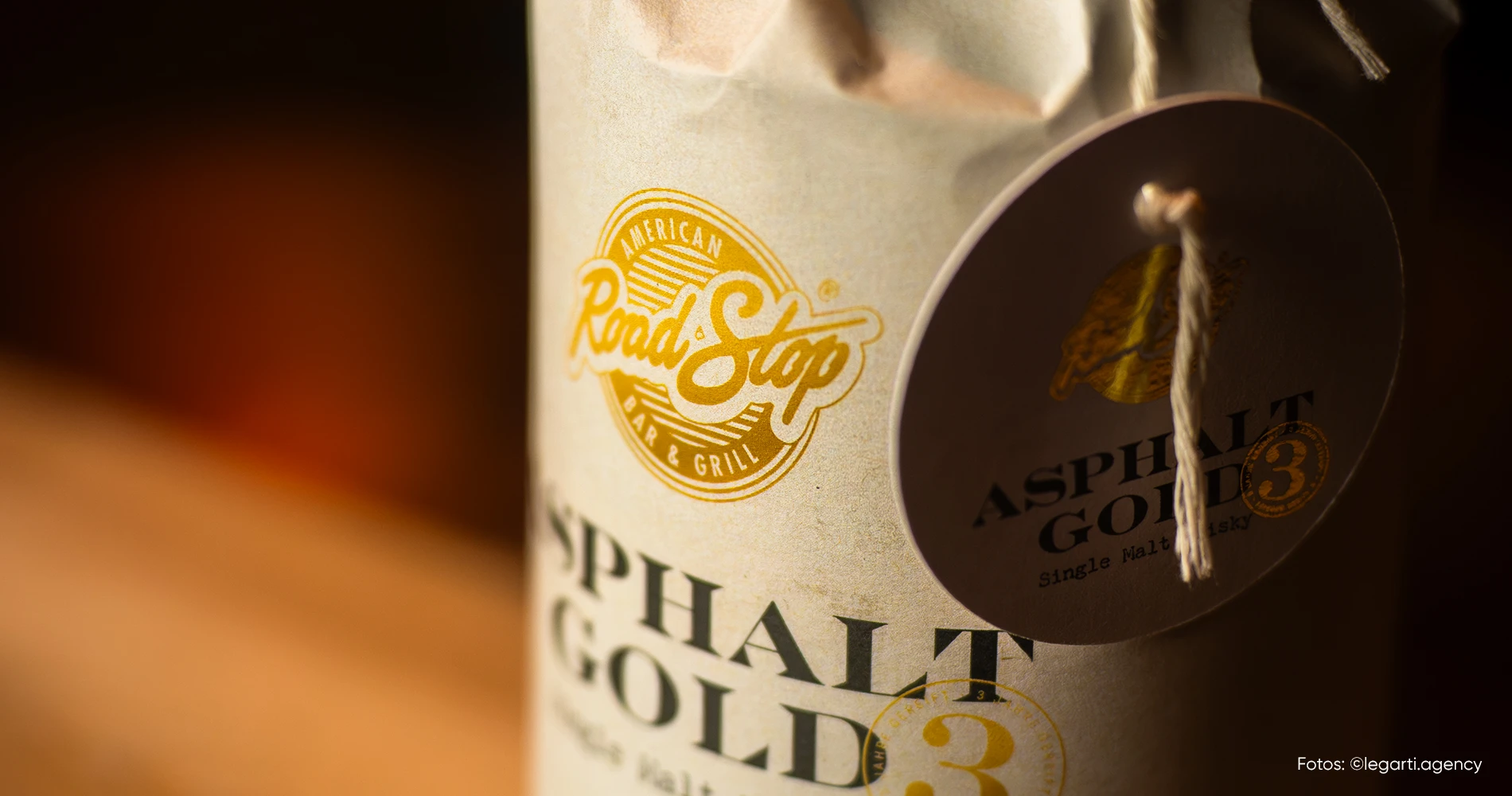 Detailaufnahme des Packagingdesigns „Asphalt Gold“ mit Etikett, Prägung und Anhänger