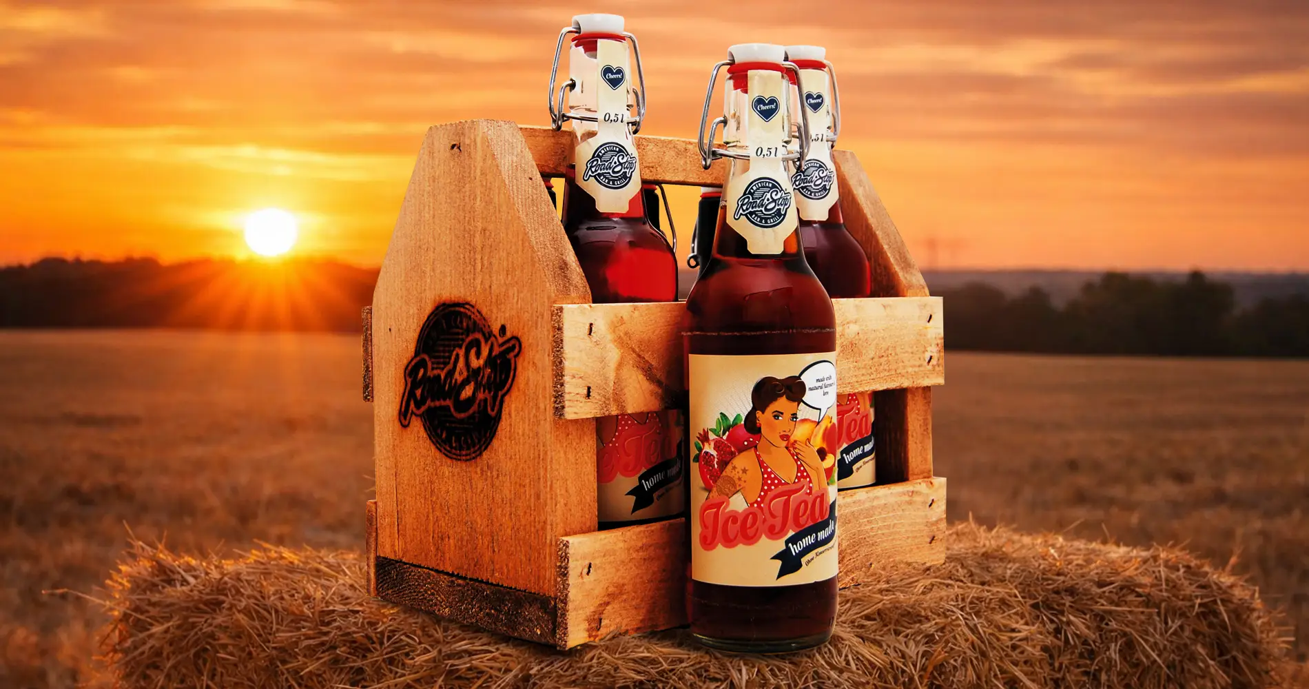 Ice-Tea-Flaschen in Holzkiste bei Sonnenuntergang auf einem Feld