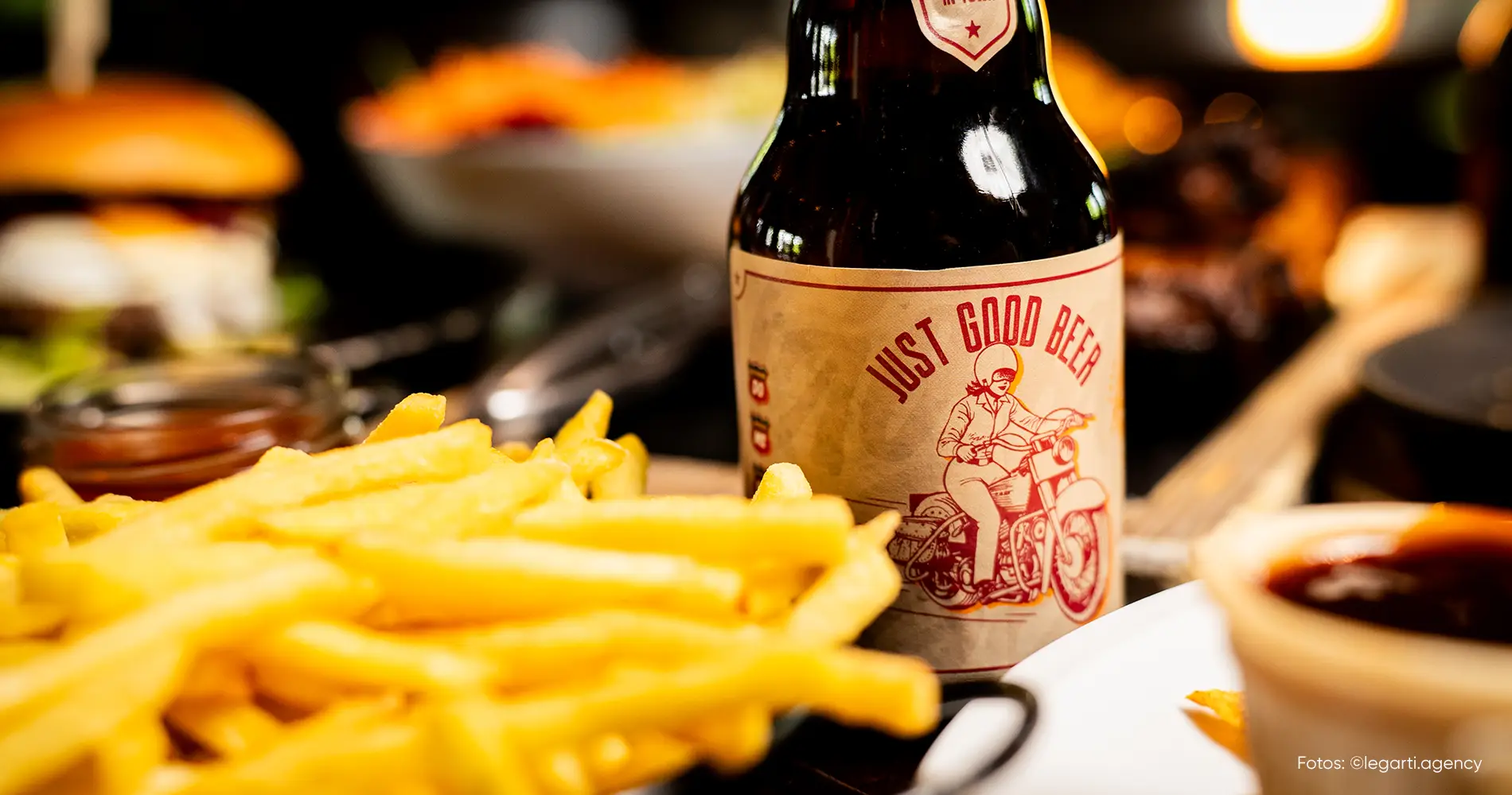 Bierflasche mit Retro-Label zwischen Pommes und Burger in Restaurantatmosphäre