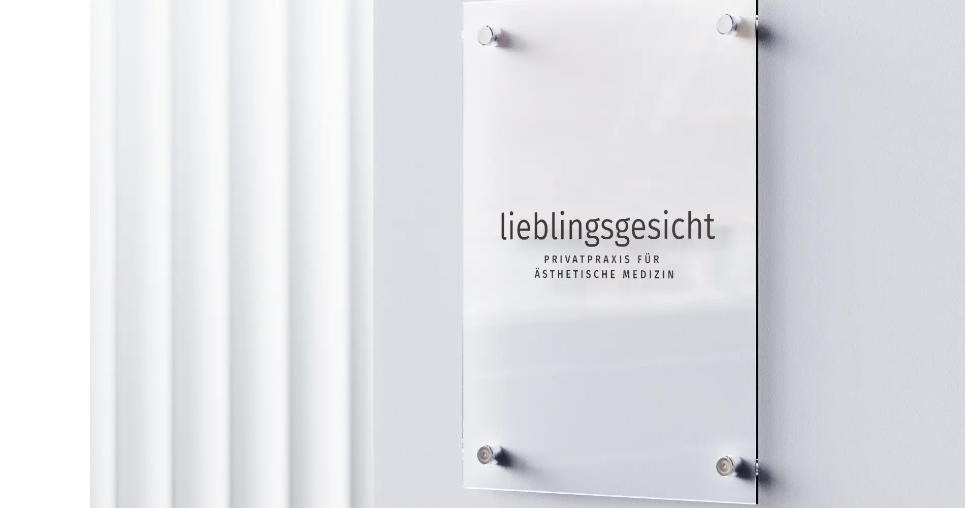 Praxisschild Lieblingsgesicht für ästhetische Medizin mit reduzierter Typografie auf Glas