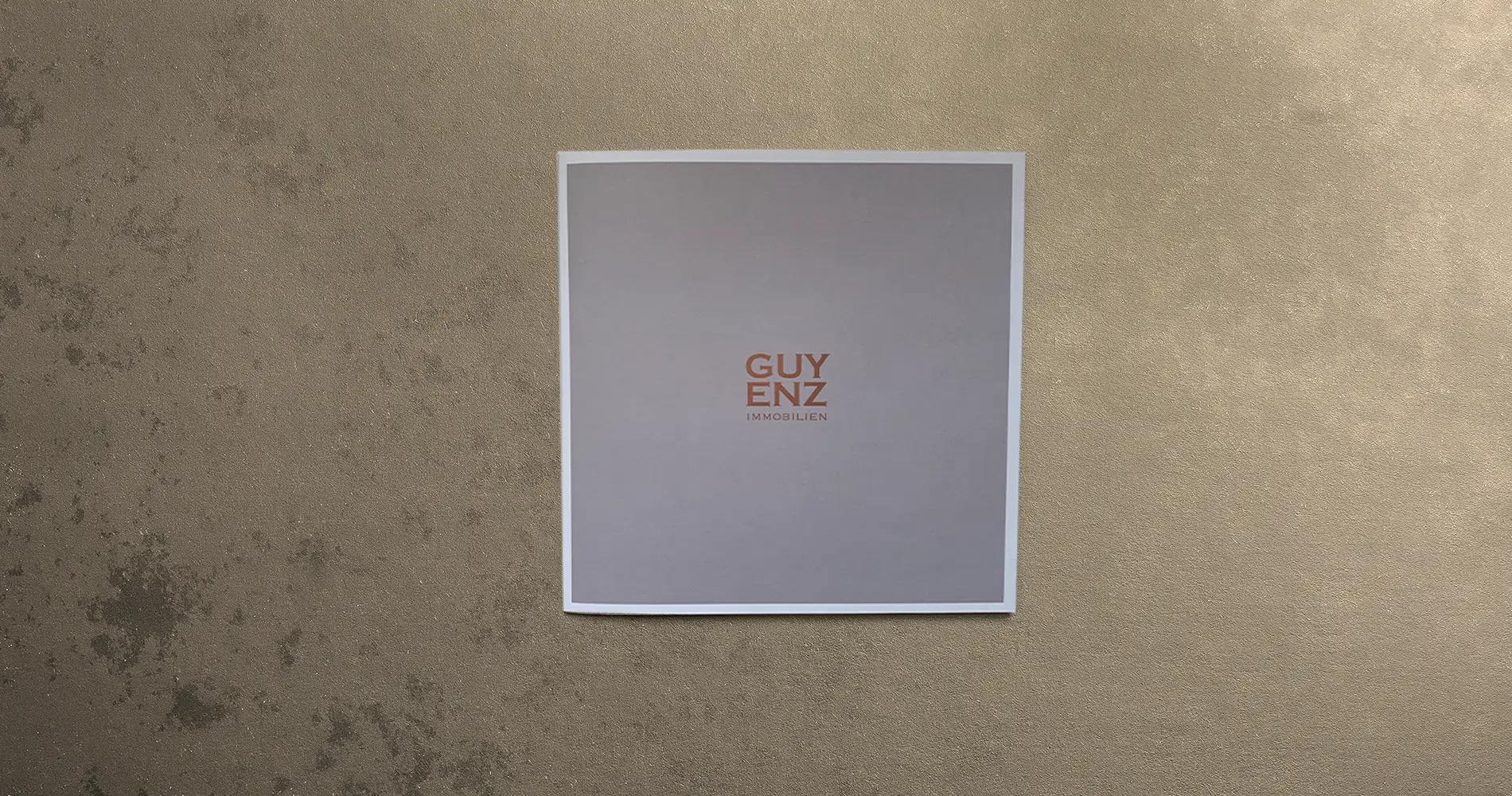 Minimalistische Broschüre mit „Guyenz Immobilien“ auf neutralem Hintergrund