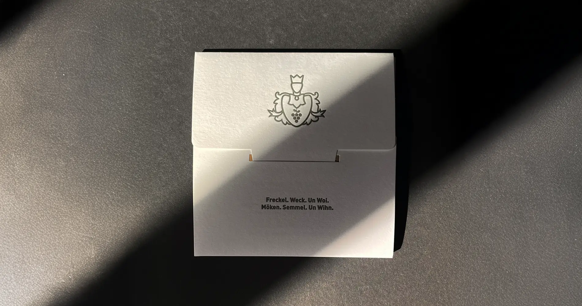 Geschlossene hochwertige Eventeinladung mit Prägung und typografischem Detail
