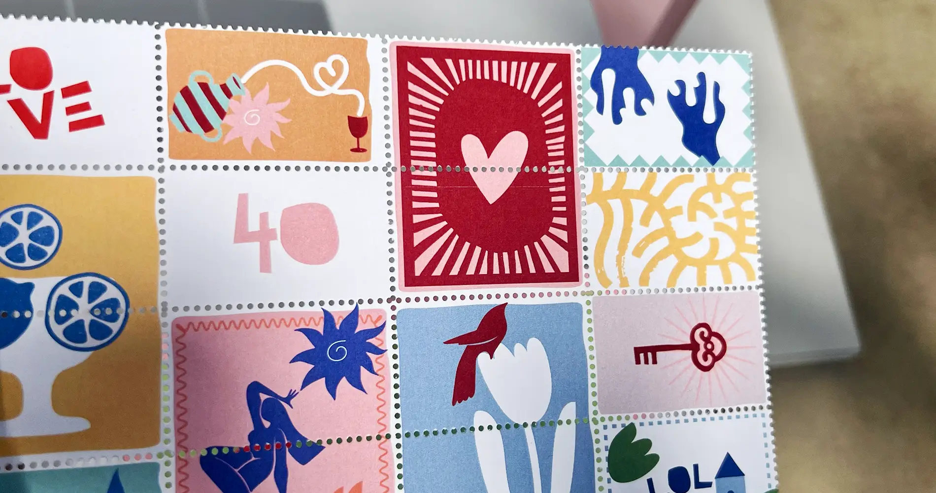 Fotografie von illustrativen Briefmarken mit bunten Love-Motiven wie Herz, Zitrusfrüchten, Vogel und grafischen Mustern