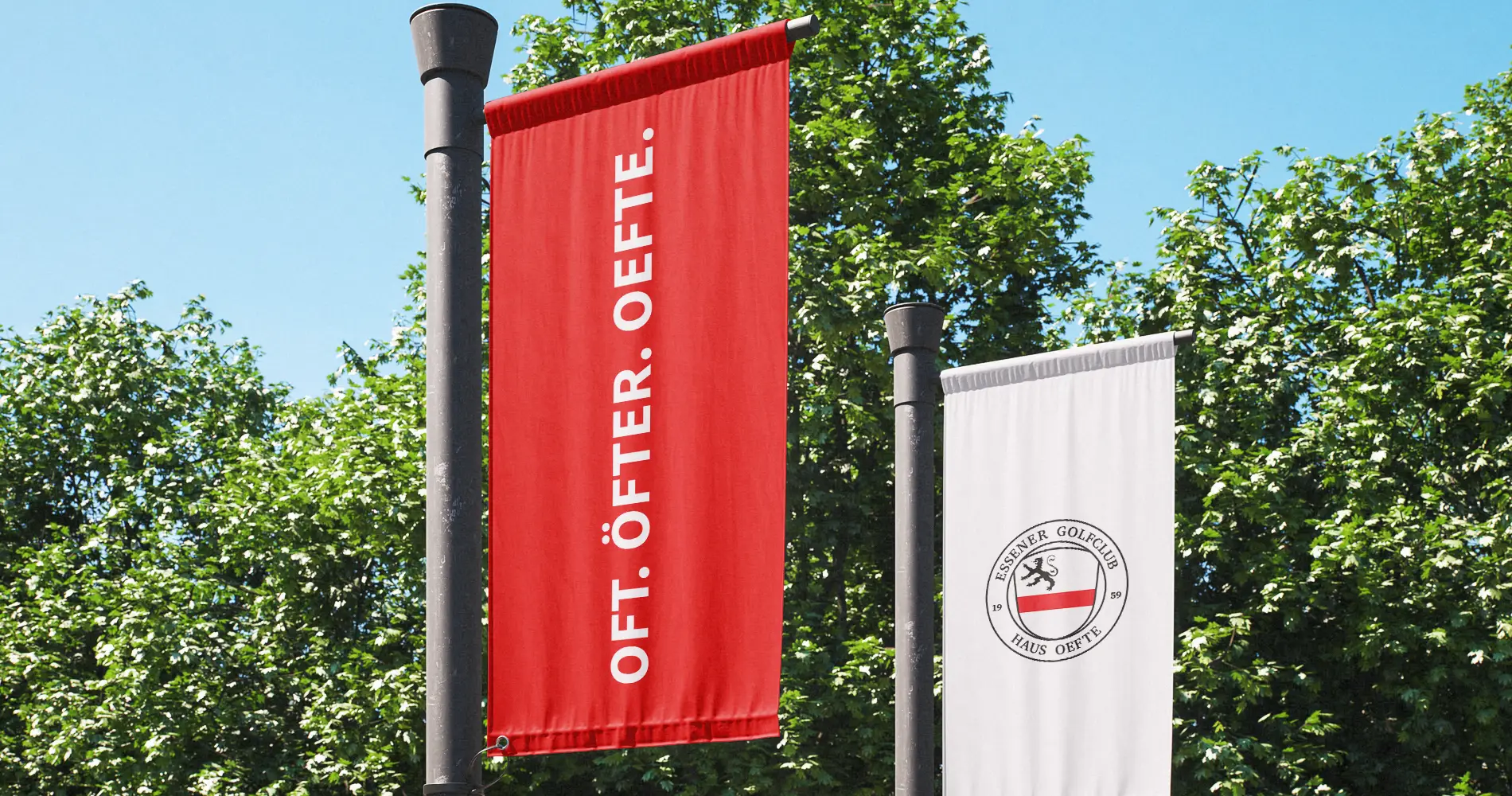Fahnen mit Branding eines Golfclubs vor Bäumen und blauem Himmel