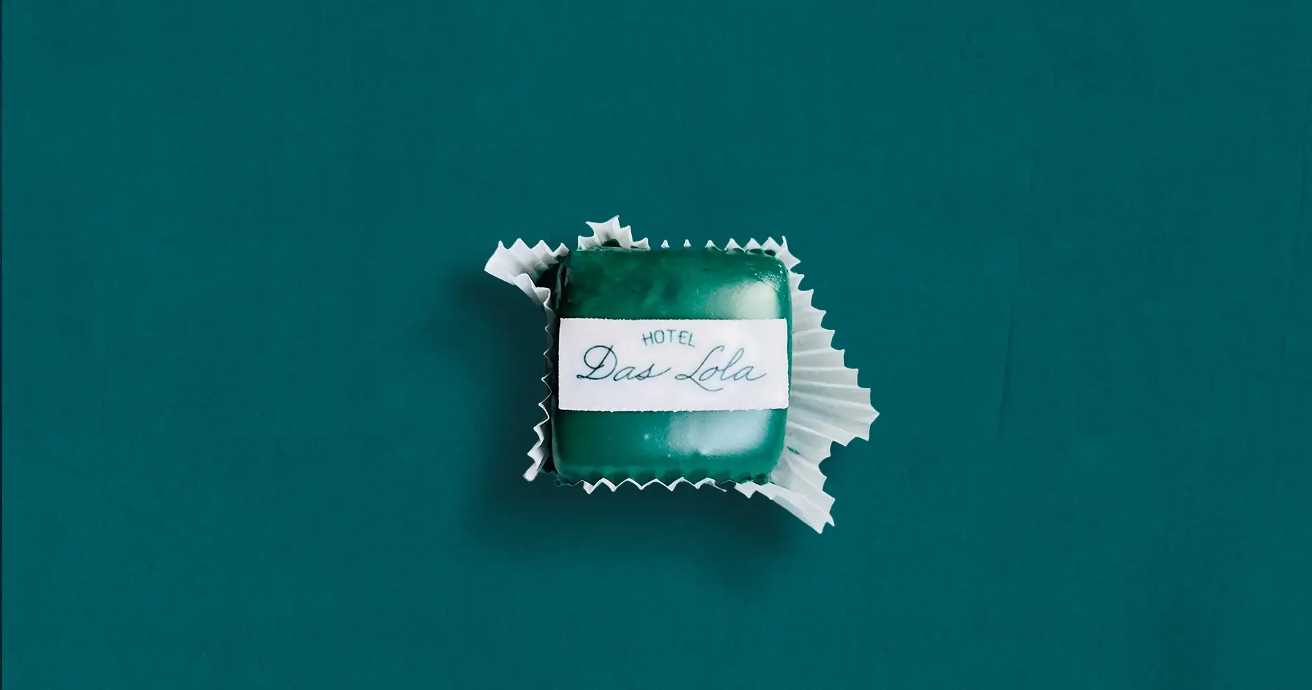 Praline mit Aufdruck ‚Hotel Das Lola‘ auf grünem Hintergrund