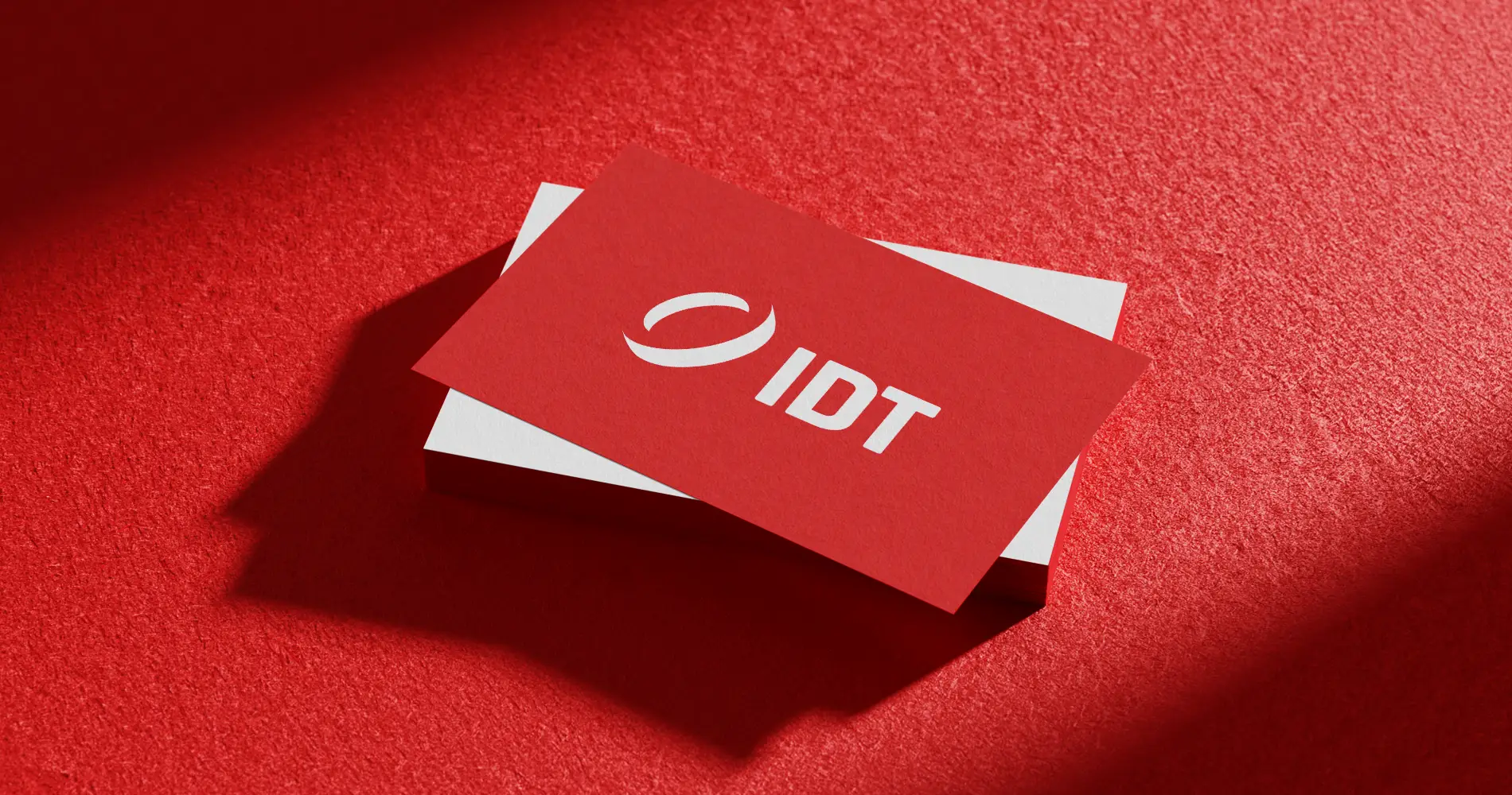 Rote Visitenkarten von IDT mit Logo auf strukturierter Oberfläche