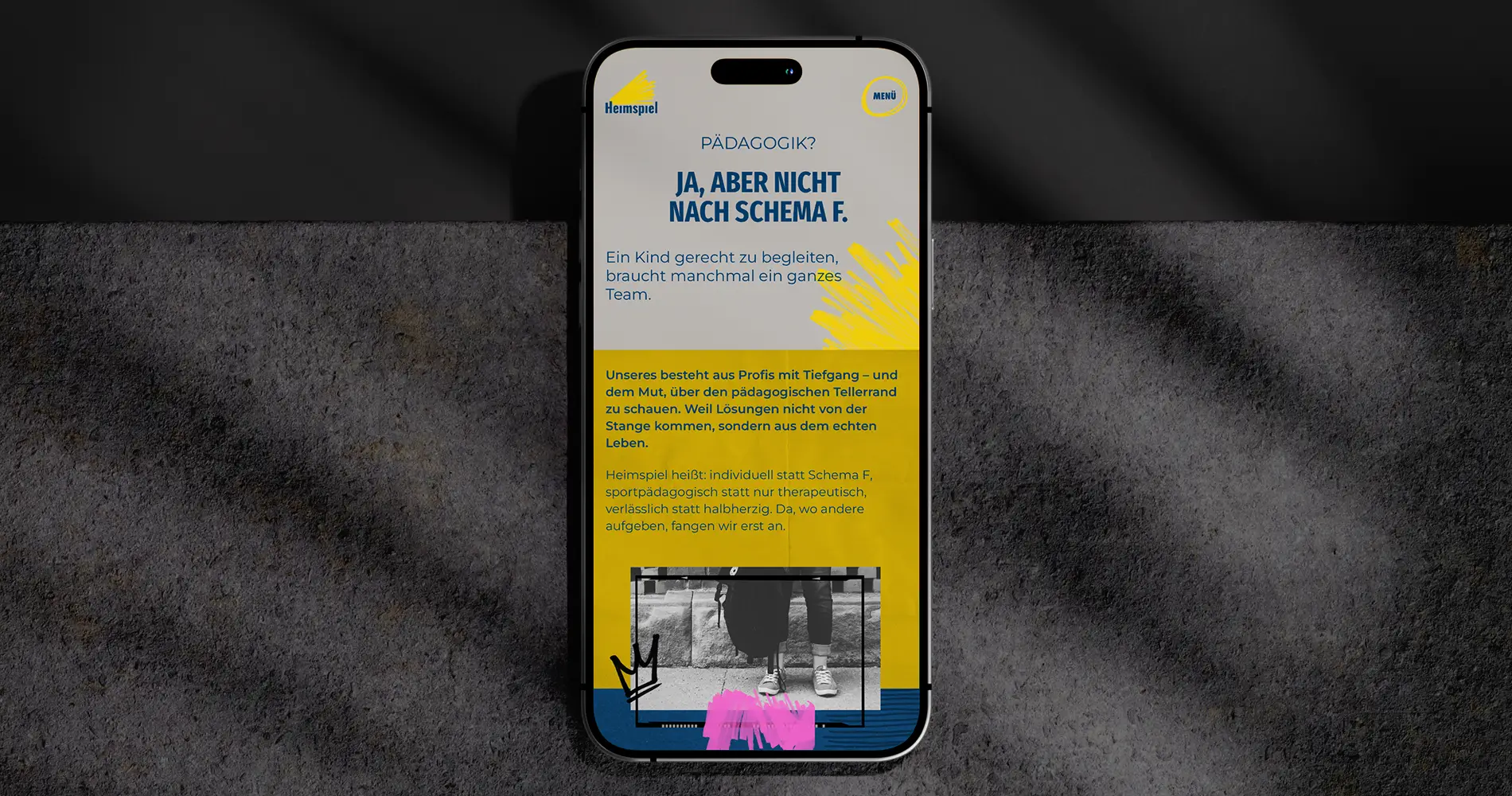 Smartphone zeigt Website von Heimspiel Jugendhilfe mit pädagogischem Leitgedanken