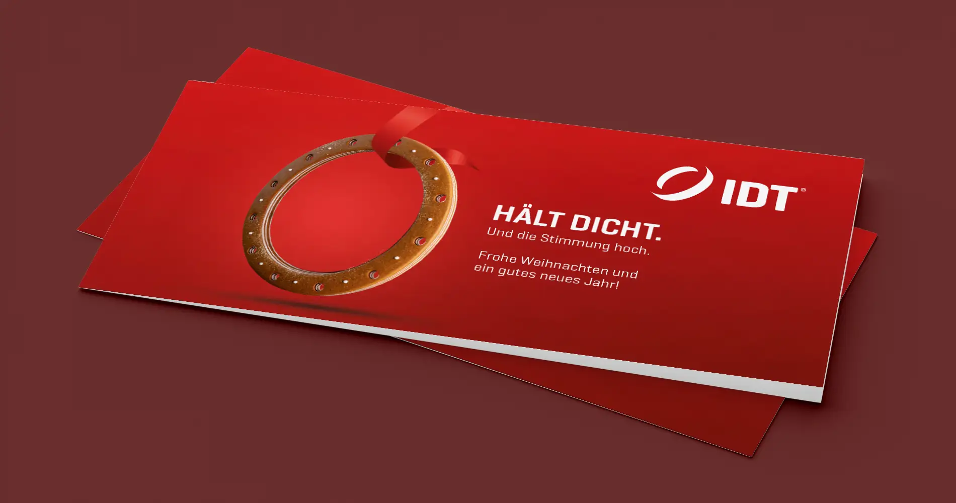 Weihnachtskarte von IDT mit rotem Design, integriertem Dichtungsring und typografischer Botschaft