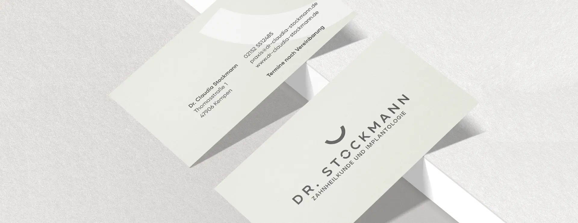 Visitenkarten mit Logo und Kontaktdaten der Zahnarztpraxis Dr. Stockmann auf hellem Hintergrund