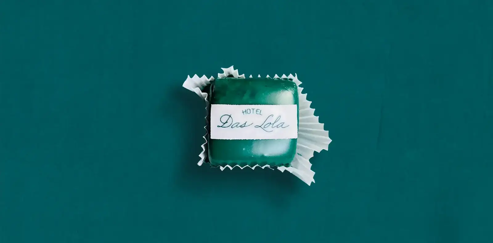 Praline mit Aufdruck ‚Hotel Das Lola‘ auf grünem Hintergrund