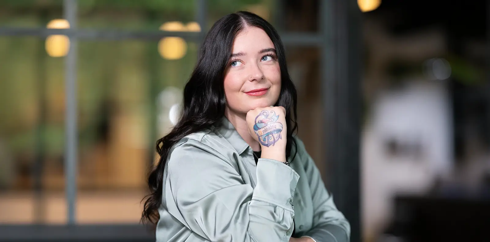 Frau zeigt lächelnd ein Tattoo auf ihrem Handrücken