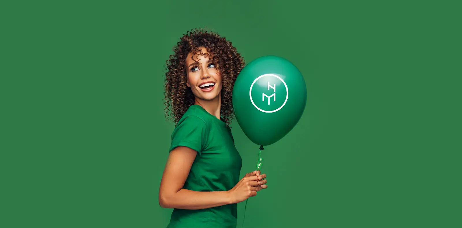Wohnszene mit grünem Sofa und Frau mit Ballon neben Logo von Möbel Hensel Markenrelaunch