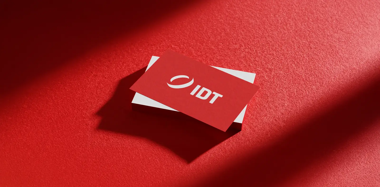 Rote Visitenkarten von IDT mit Logo auf strukturierter Oberfläche