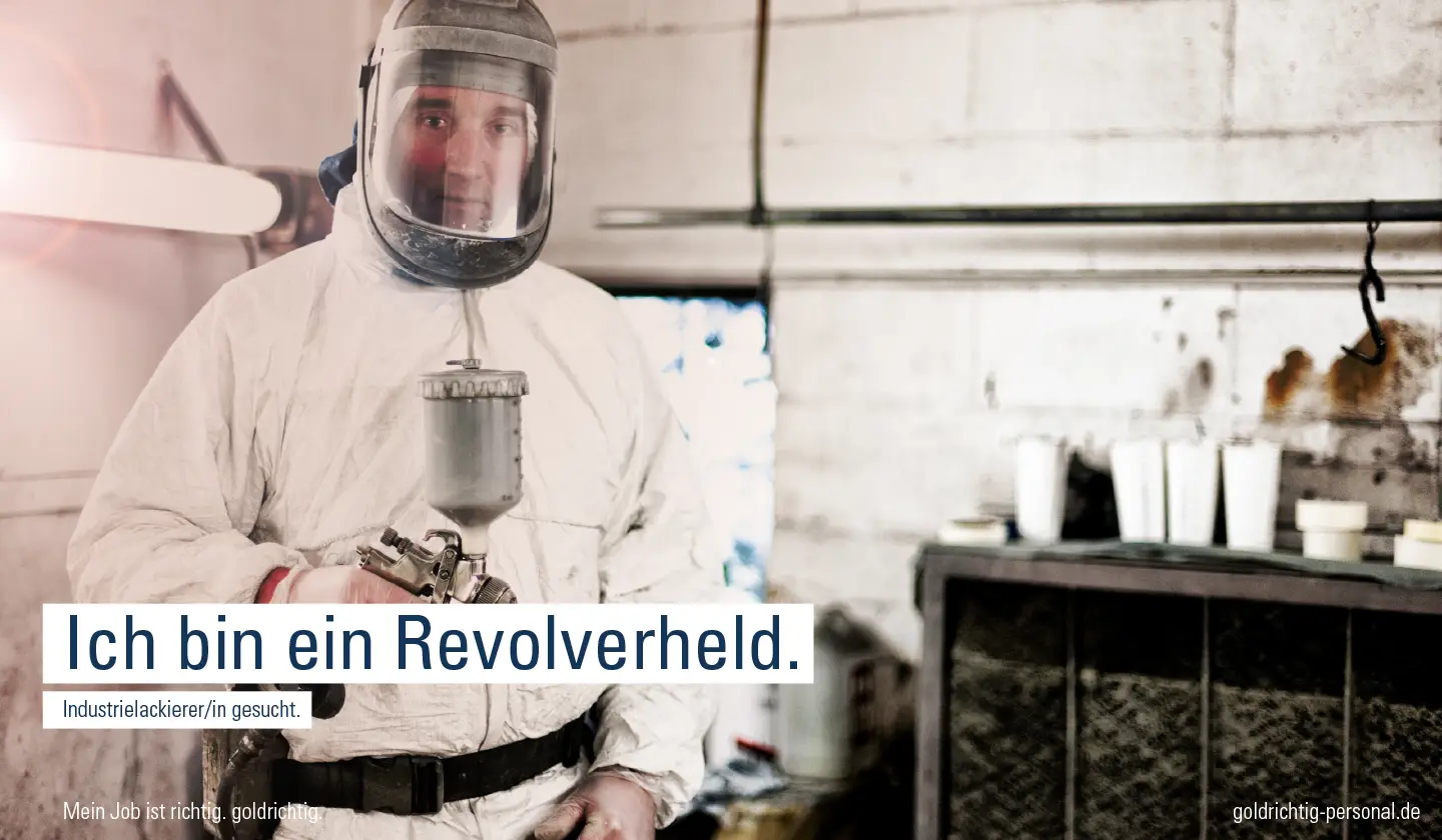 Industrielackierer mit Spritzpistole in Schutzkleidung bei der Arbeit mit Kampagnenbotschaft „Ich bin ein Revolverheld“