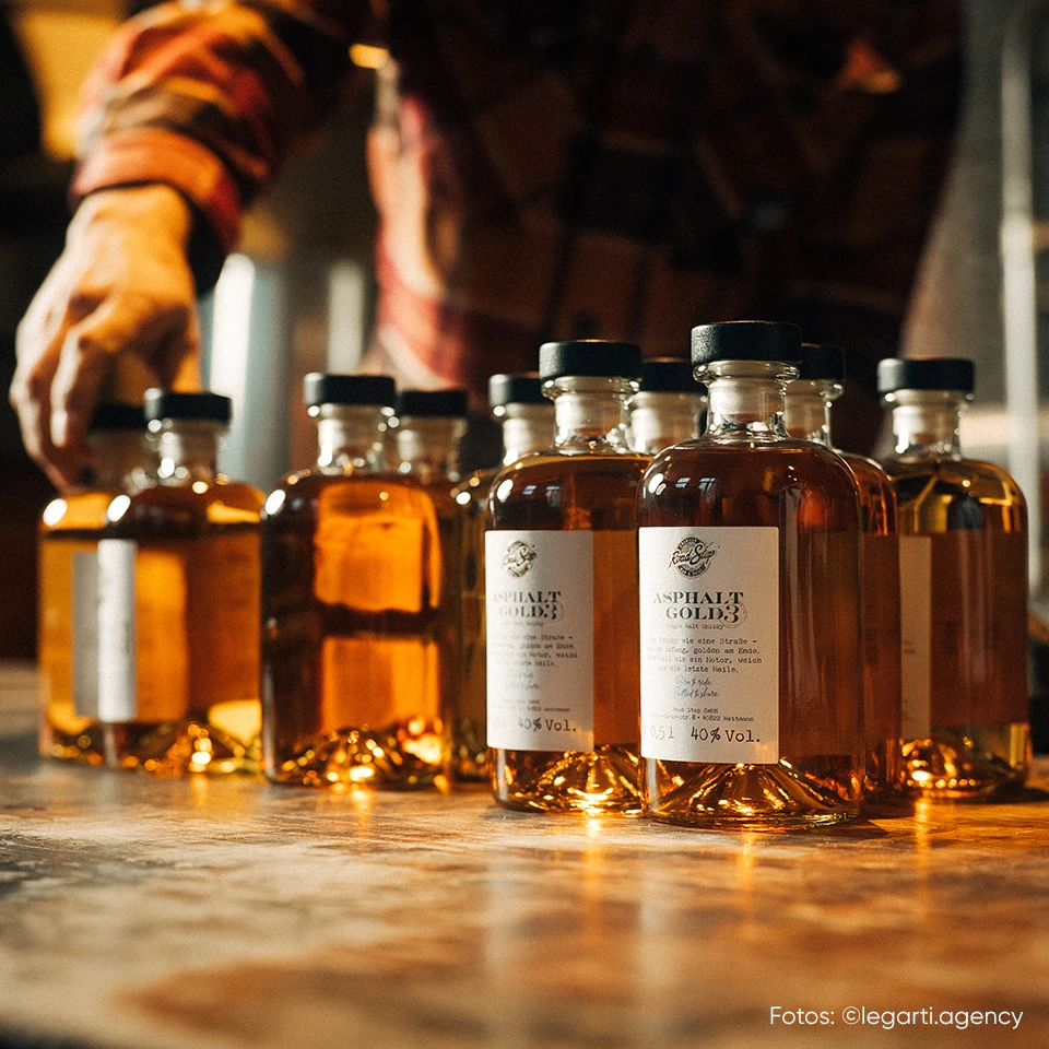 Mehrere Whiskyflaschen auf einem Tisch, im Hintergrund eine Person bei der Arbeit